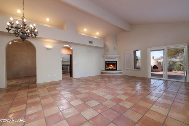 unfurnished living room featuring light tile patterned floors, high vaulted ceiling, a chandelier, a fireplace, and beamed ceiling