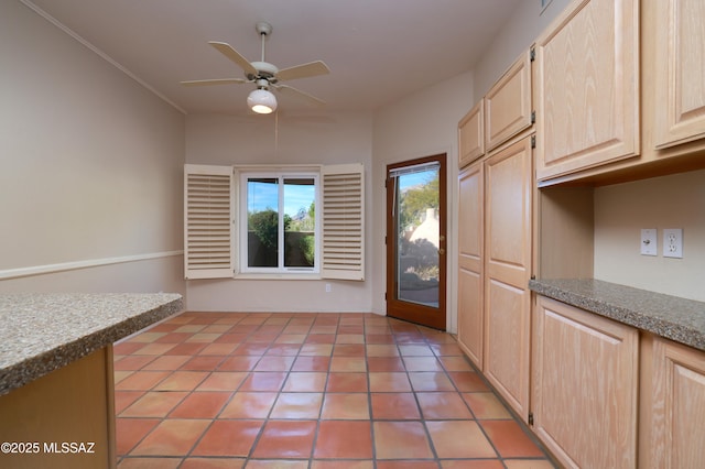 unfurnished dining area featuring ceiling fan and light brown cabinetry