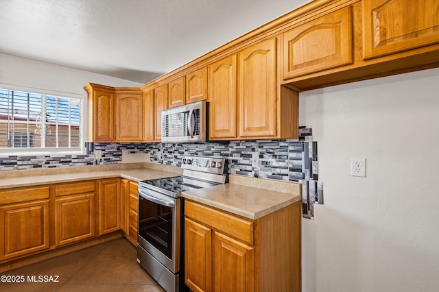 kitchen featuring decorative backsplash, dark tile patterned flooring, and appliances with stainless steel finishes