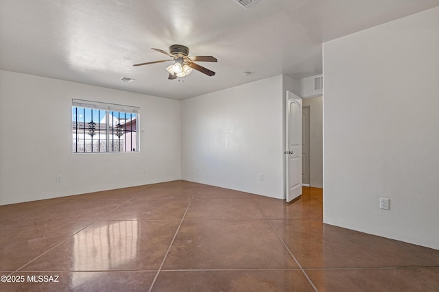 empty room with ceiling fan and dark tile patterned floors