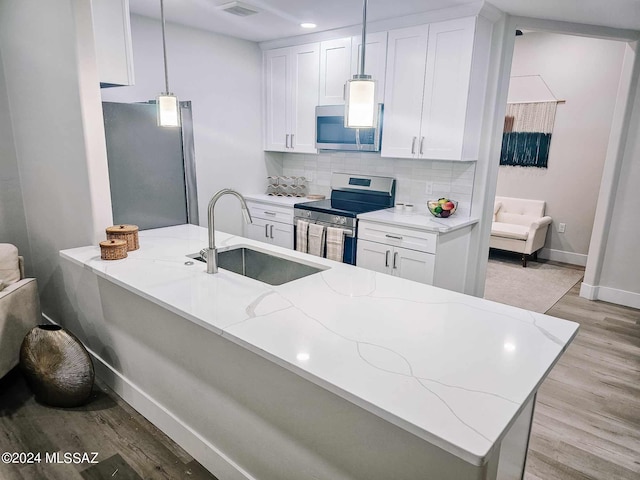 kitchen with light stone countertops, sink, pendant lighting, and appliances with stainless steel finishes