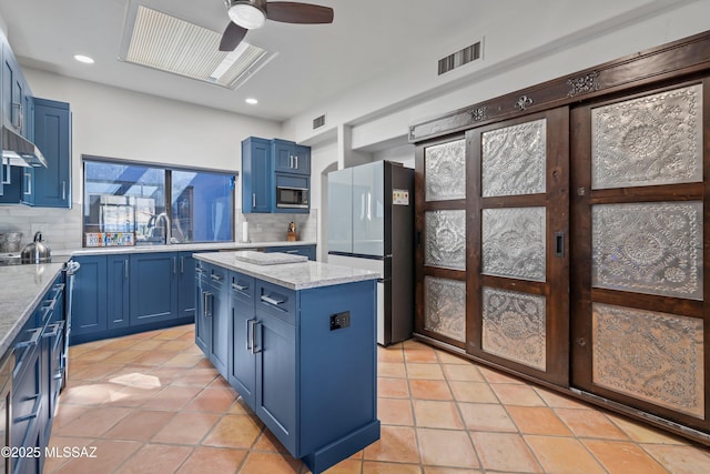 kitchen featuring blue cabinets, refrigerator, and black microwave