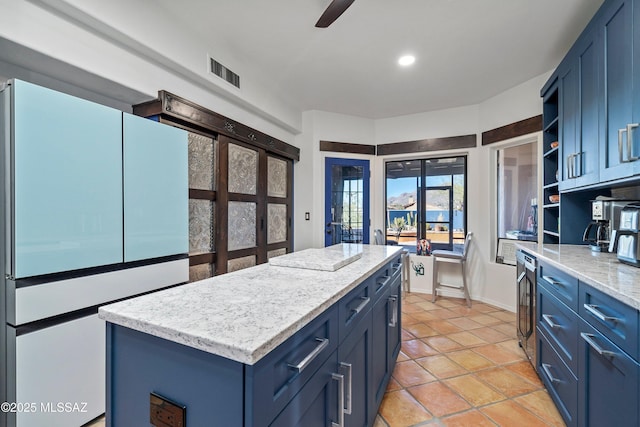 kitchen with refrigerator, ceiling fan, light tile patterned floors, blue cabinetry, and a kitchen island