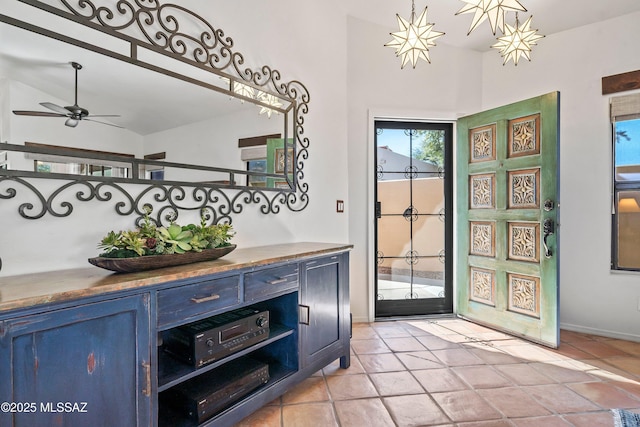 foyer entrance with lofted ceiling, ceiling fan, and light tile patterned floors