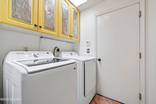 laundry room featuring washing machine and clothes dryer, light tile patterned floors, and cabinets