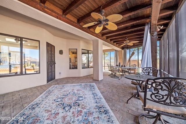 sunroom featuring wood ceiling, ceiling fan, and beamed ceiling