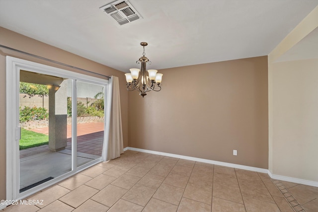 empty room with light tile patterned floors and a chandelier