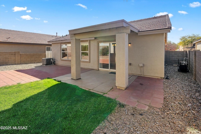 back of property with a patio area, central air condition unit, and a yard