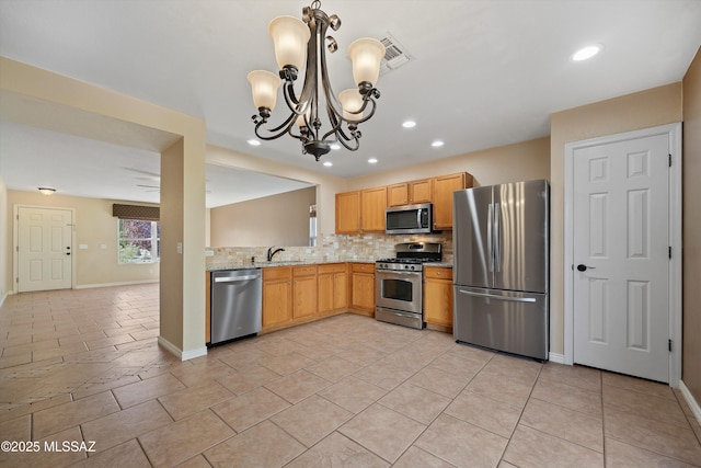 kitchen with appliances with stainless steel finishes, tasteful backsplash, light stone countertops, a chandelier, and sink