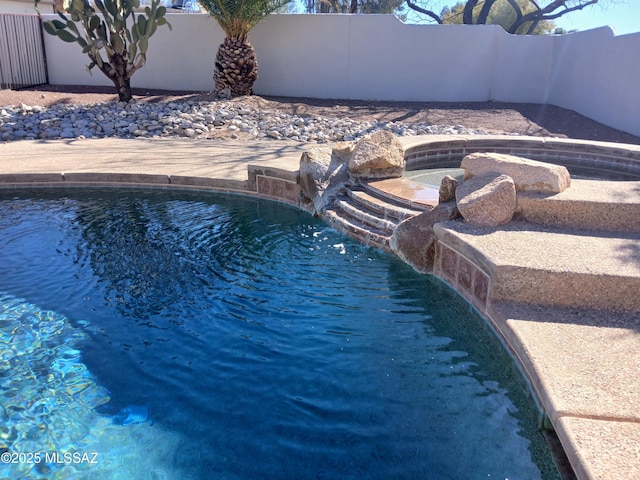 view of swimming pool featuring a hot tub, fence, and a fenced in pool