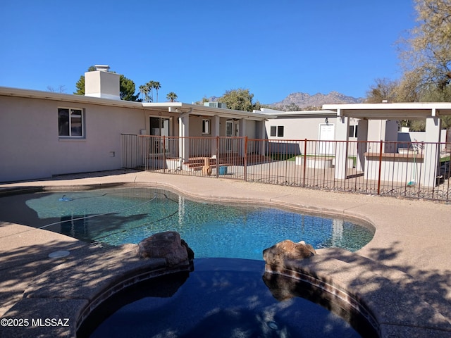 view of pool with a patio, fence, and a pool with connected hot tub