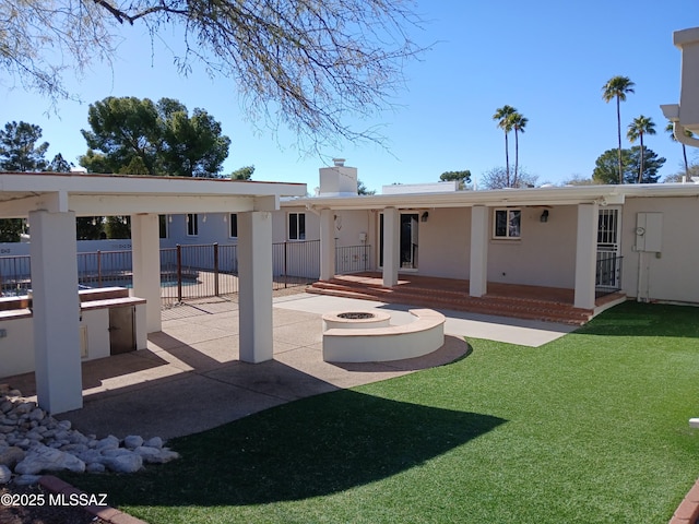 back of property with a patio, a chimney, stucco siding, an outdoor fire pit, and fence