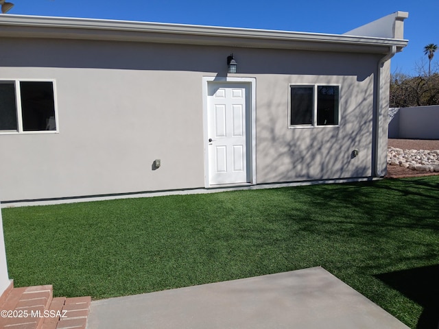 back of property featuring a lawn and stucco siding