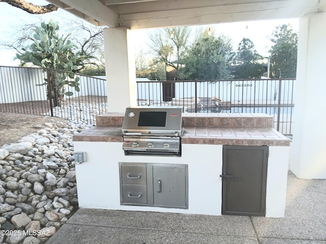 view of patio with exterior kitchen, fence, and area for grilling