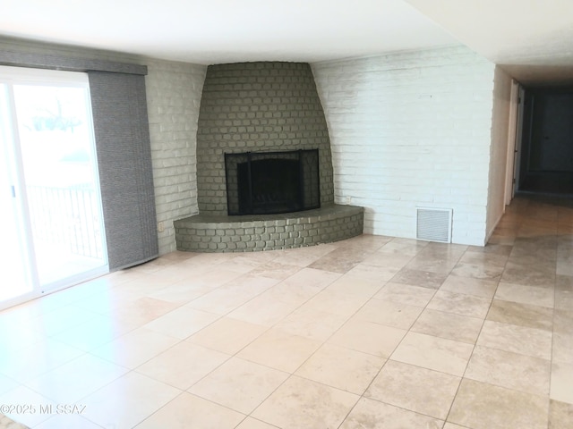 unfurnished living room with light tile patterned floors, brick wall, a brick fireplace, and visible vents