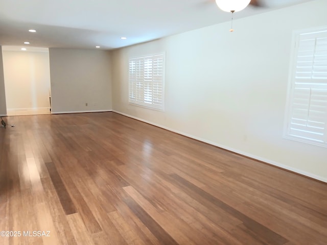 unfurnished room with baseboards, wood finished floors, and recessed lighting