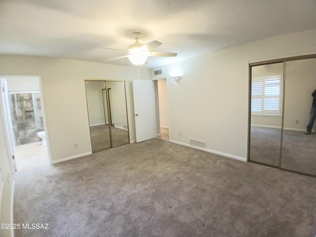 unfurnished bedroom with connected bathroom, carpet flooring, visible vents, baseboards, and multiple closets