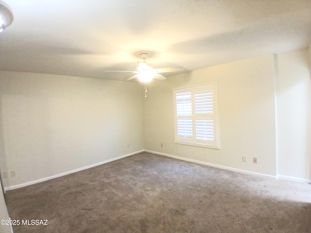 spare room featuring dark carpet, baseboards, and ceiling fan