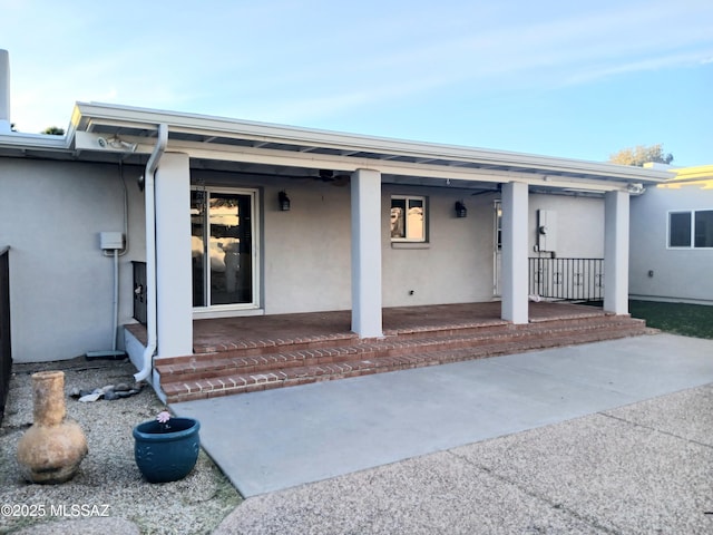 entrance to property with covered porch, a patio area, and stucco siding