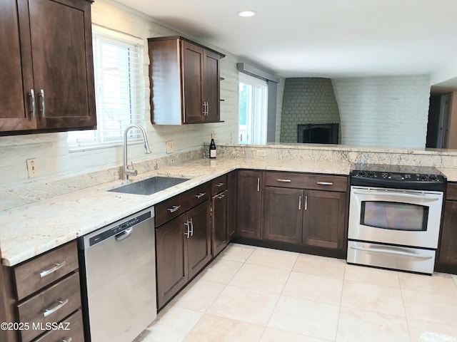 kitchen featuring appliances with stainless steel finishes, plenty of natural light, a sink, and dark brown cabinetry