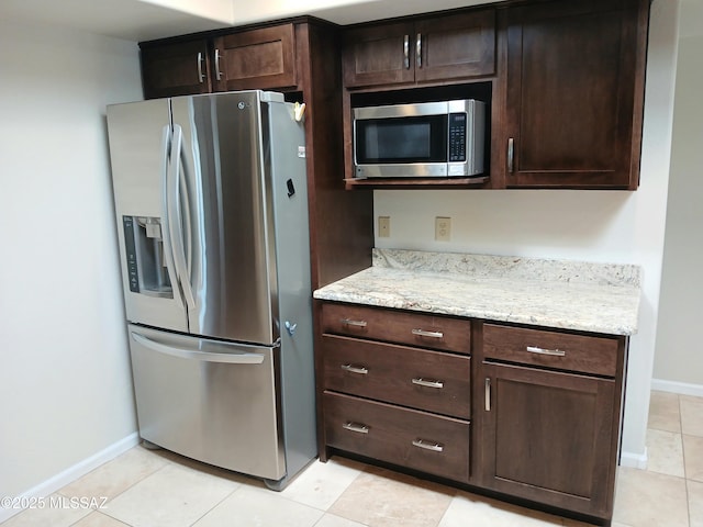 kitchen with dark brown cabinetry, baseboards, appliances with stainless steel finishes, and light stone counters