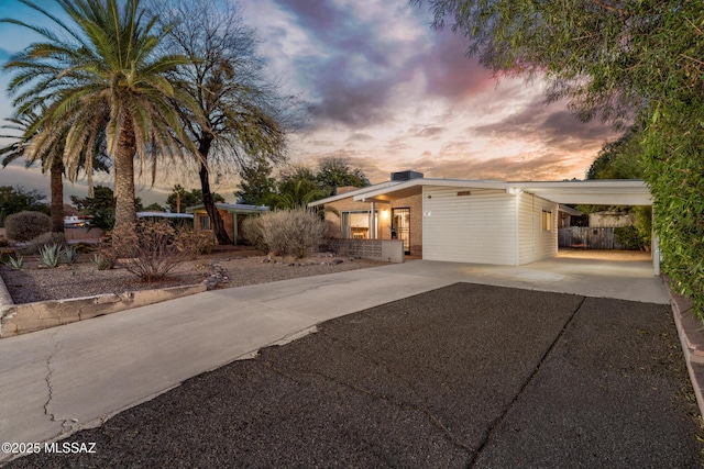 mid-century inspired home with driveway and a carport