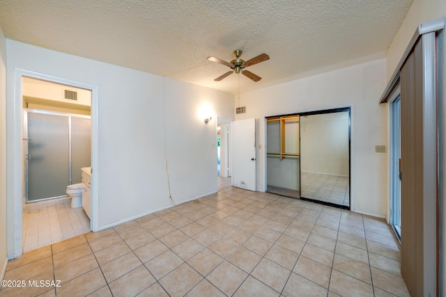 unfurnished bedroom with light tile patterned floors, a closet, visible vents, a barn door, and a textured ceiling