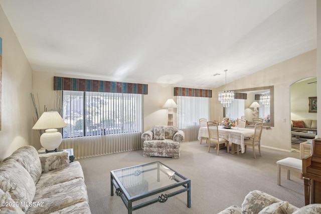 carpeted living room with lofted ceiling and a notable chandelier