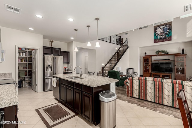 kitchen featuring dark brown cabinetry, sink, an island with sink, pendant lighting, and stainless steel appliances