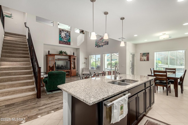 kitchen with sink, a center island with sink, light tile patterned floors, dishwasher, and pendant lighting