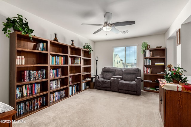 living area featuring light carpet and ceiling fan