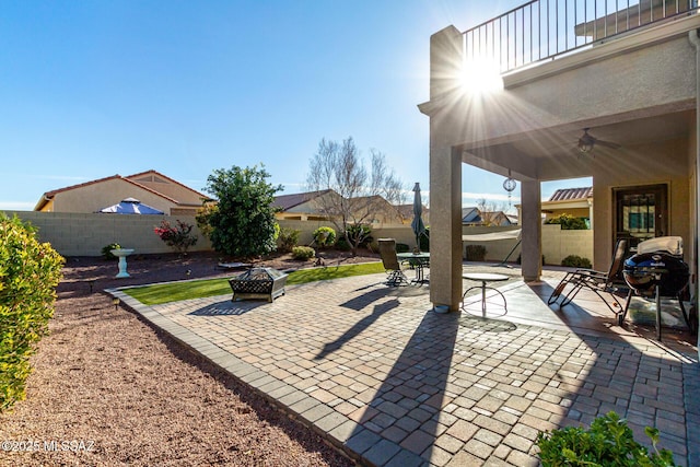 view of patio / terrace with a balcony, ceiling fan, and an outdoor fire pit