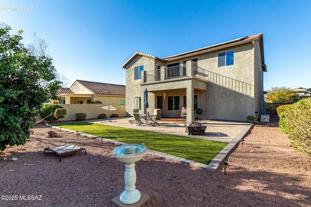 rear view of property featuring a balcony, an outdoor fire pit, and a patio area