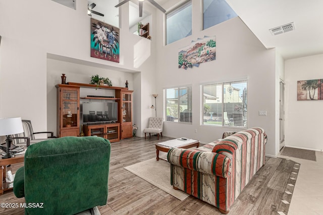 living room with a towering ceiling, ceiling fan, and hardwood / wood-style flooring