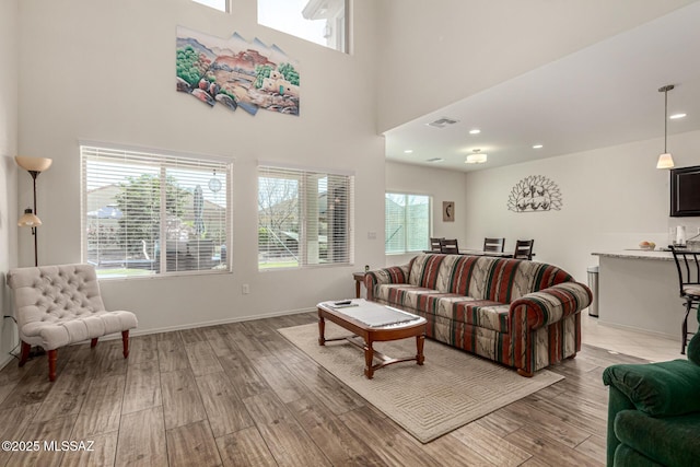 living room with plenty of natural light, a towering ceiling, and light wood-type flooring