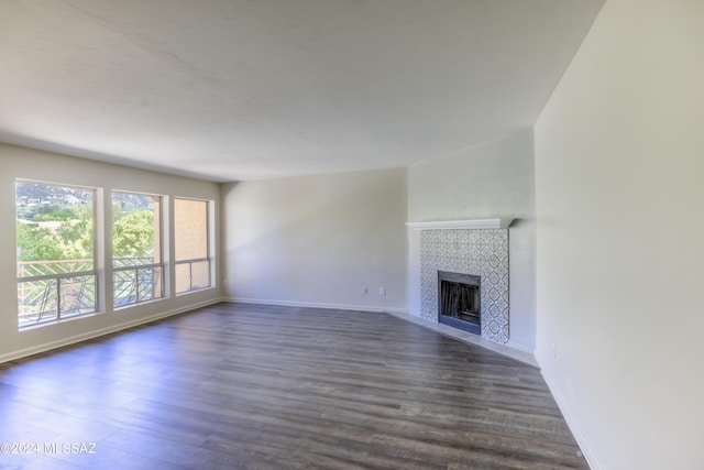 unfurnished living room featuring a tile fireplace and dark wood-type flooring