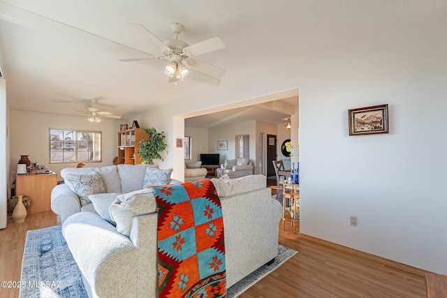 living room with light hardwood / wood-style floors, ceiling fan, and vaulted ceiling