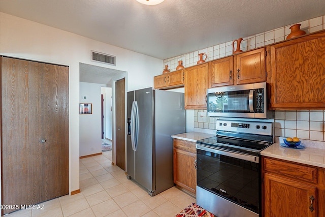 kitchen with a textured ceiling, tasteful backsplash, and appliances with stainless steel finishes