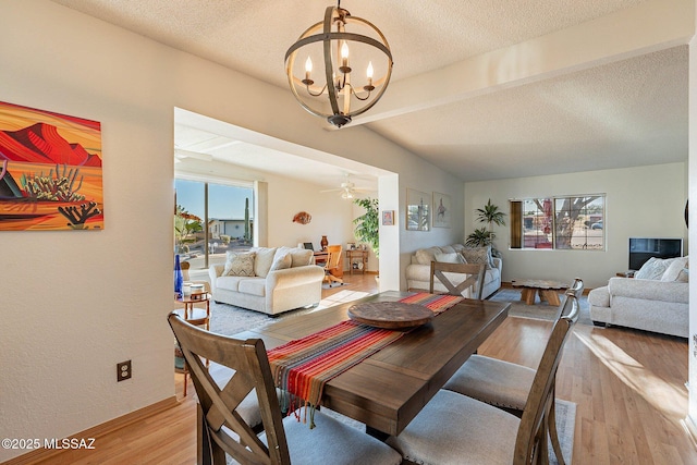 dining room with ceiling fan with notable chandelier, hardwood / wood-style floors, a textured ceiling, and lofted ceiling with beams