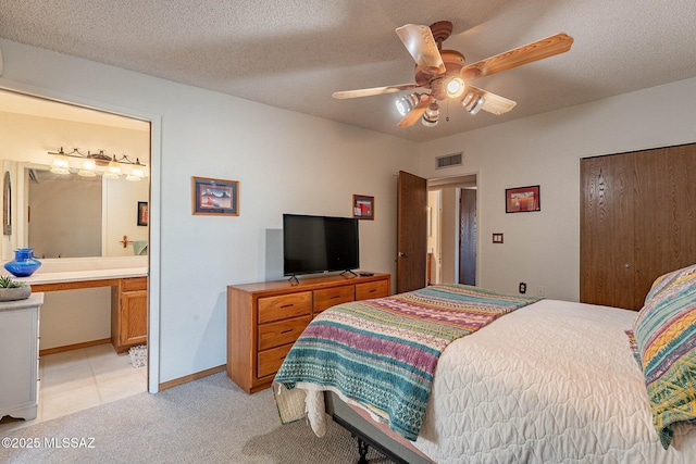 carpeted bedroom with a textured ceiling, connected bathroom, and ceiling fan