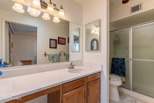 bathroom featuring tile patterned flooring, toilet, a shower with door, and vanity