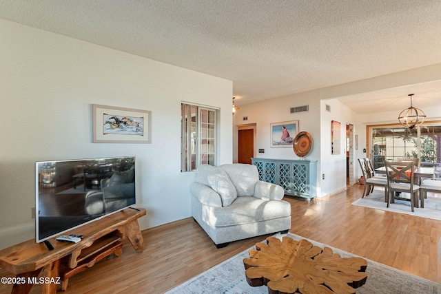 living room featuring hardwood / wood-style floors, an inviting chandelier, and a textured ceiling