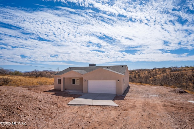 view of front facade with a garage, concrete driveway, and stucco siding