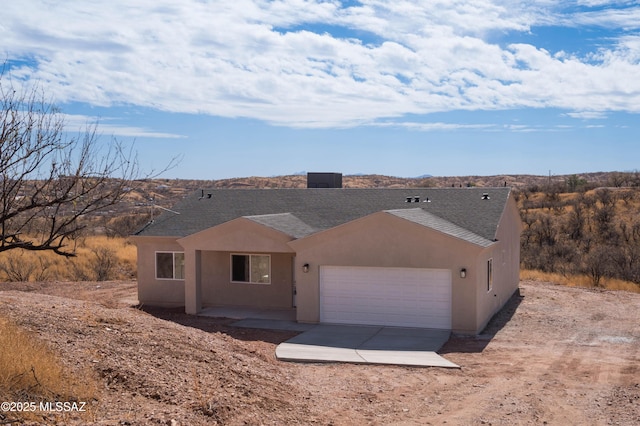 view of front of home featuring a garage, concrete driveway, roof with shingles, and stucco siding