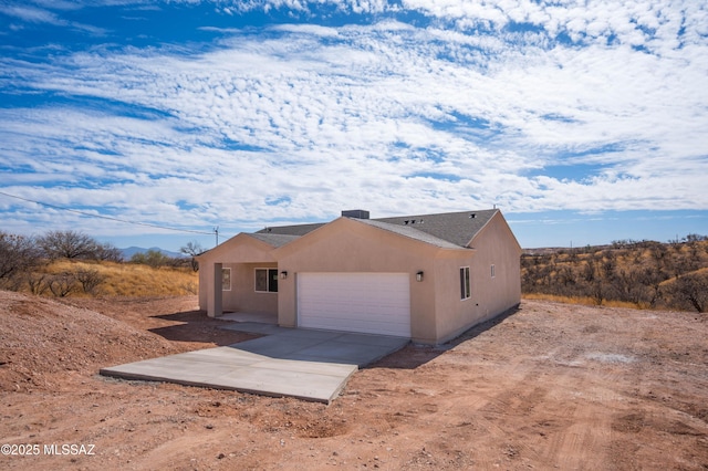 view of side of property featuring a garage, concrete driveway, and stucco siding