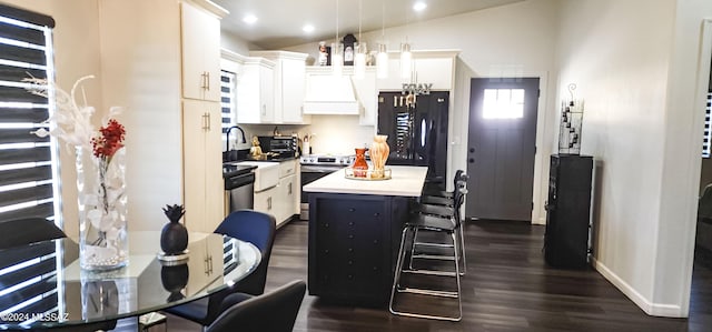 kitchen featuring stainless steel appliances, decorative light fixtures, a center island, white cabinetry, and lofted ceiling