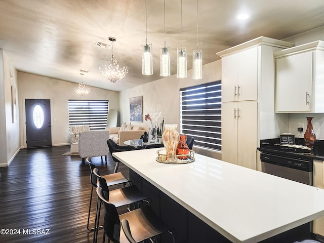 kitchen with stainless steel dishwasher, dark hardwood / wood-style floors, vaulted ceiling, decorative light fixtures, and white cabinets