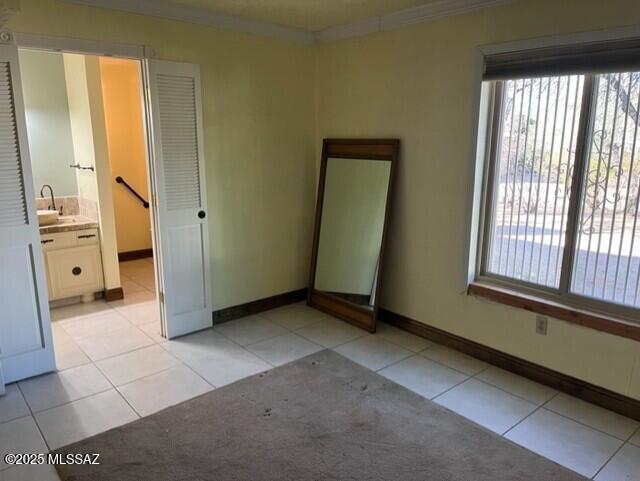 tiled spare room with sink and crown molding