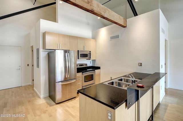 kitchen featuring sink, appliances with stainless steel finishes, a towering ceiling, beamed ceiling, and light brown cabinets