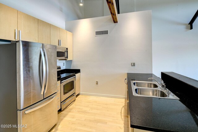 kitchen with sink, light brown cabinets, stainless steel appliances, and light wood-type flooring